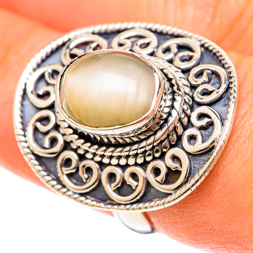 Oval moonstone cabochon ring with silver filigree and braided bezel on hand