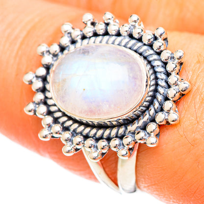 Silver moonstone ring with oval iridescent center and raised bead frame on finger