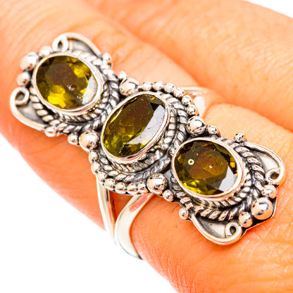 Sterling silver tourmaline ring on finger with three oval green gemstones and bead trim