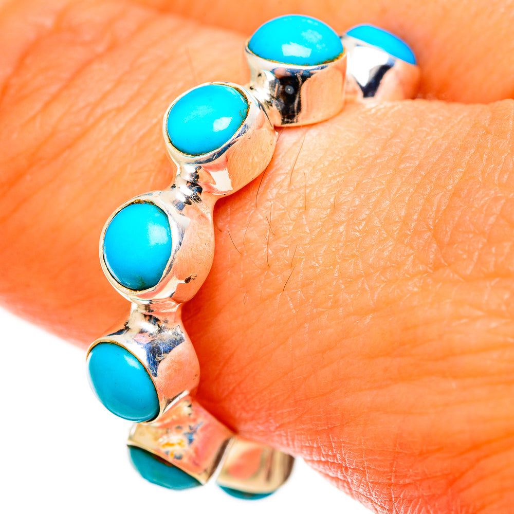 Turquoise cabochon bezel ring on finger, silver band with oval stone accents