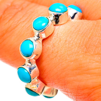 Turquoise cabochon bezel ring on finger, silver band with oval stone accents