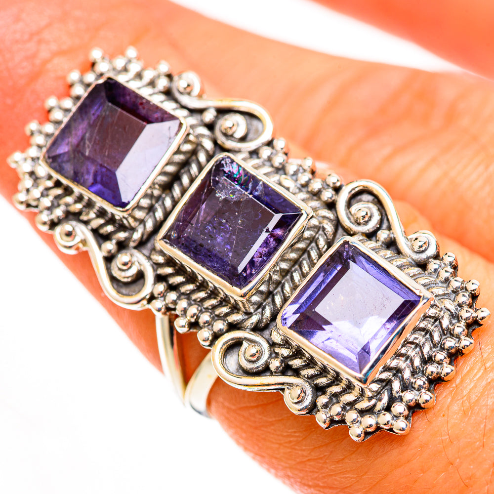 Ornate statement ring with three faceted violet-purple stones and scrollwork metal setting