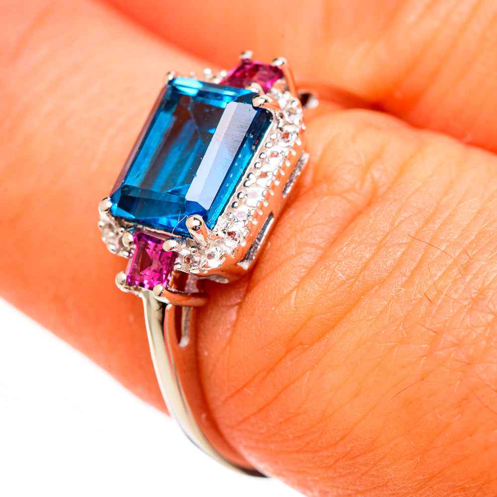 Sterling silver ring with emerald-cut blue stone, pink accents, and clear halo detail
