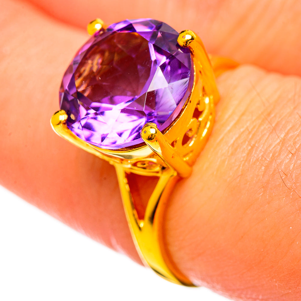 Gold-plated amethyst ring close-up with faceted purple oval gemstone on finger