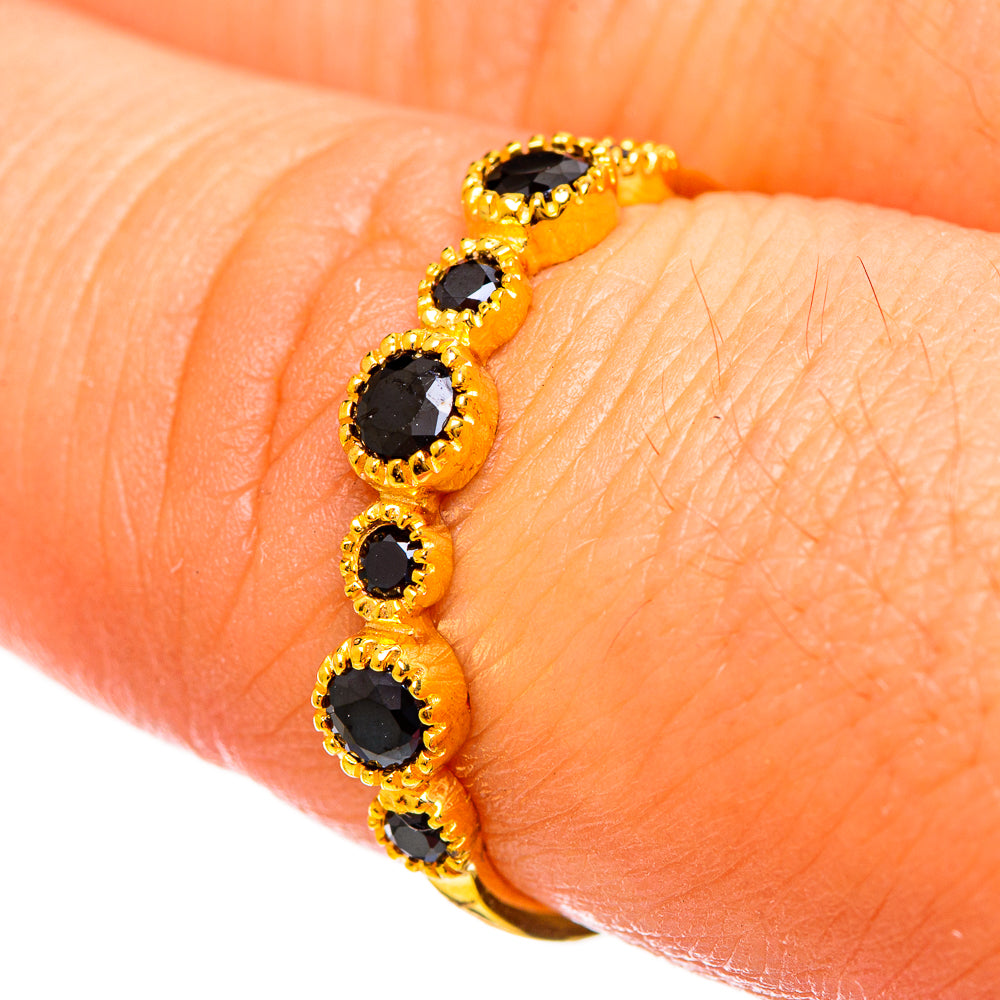 Gold-plated ring on finger with four black oval onyx stones in beaded gold bezels