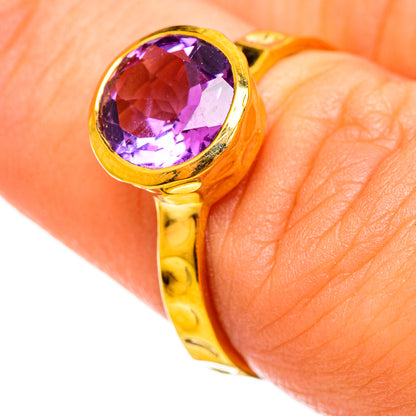 Gold-plated oval amethyst ring on finger, faceted purple stone in bezel setting