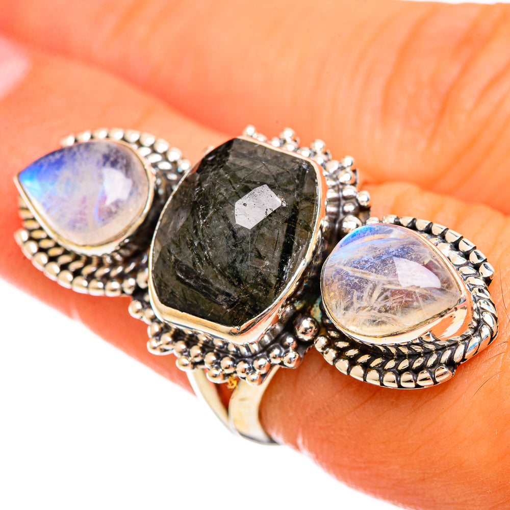Sterling silver ring with dark green faceted center stone and two oval rainbow moonstones.