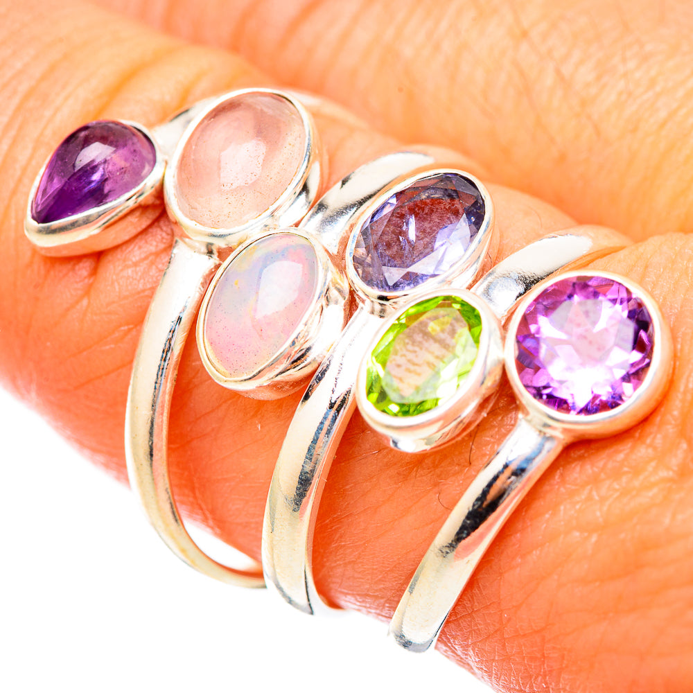 Silver-tone ring worn on finger with opal, purple amethyst, blue gem and green peridot