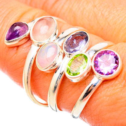 Silver-tone ring worn on finger with opal, purple amethyst, blue gem and green peridot
