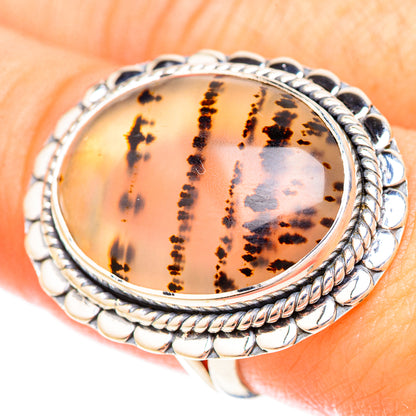 Oval amber Montana agate sterling silver rope ring on finger, dark speckled design