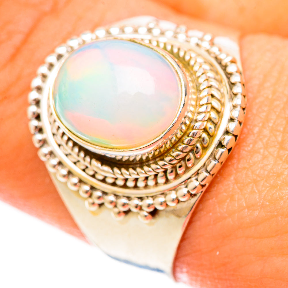 Oval opal ring with rainbow sheen, ornate rope and bead metalwork, close-up