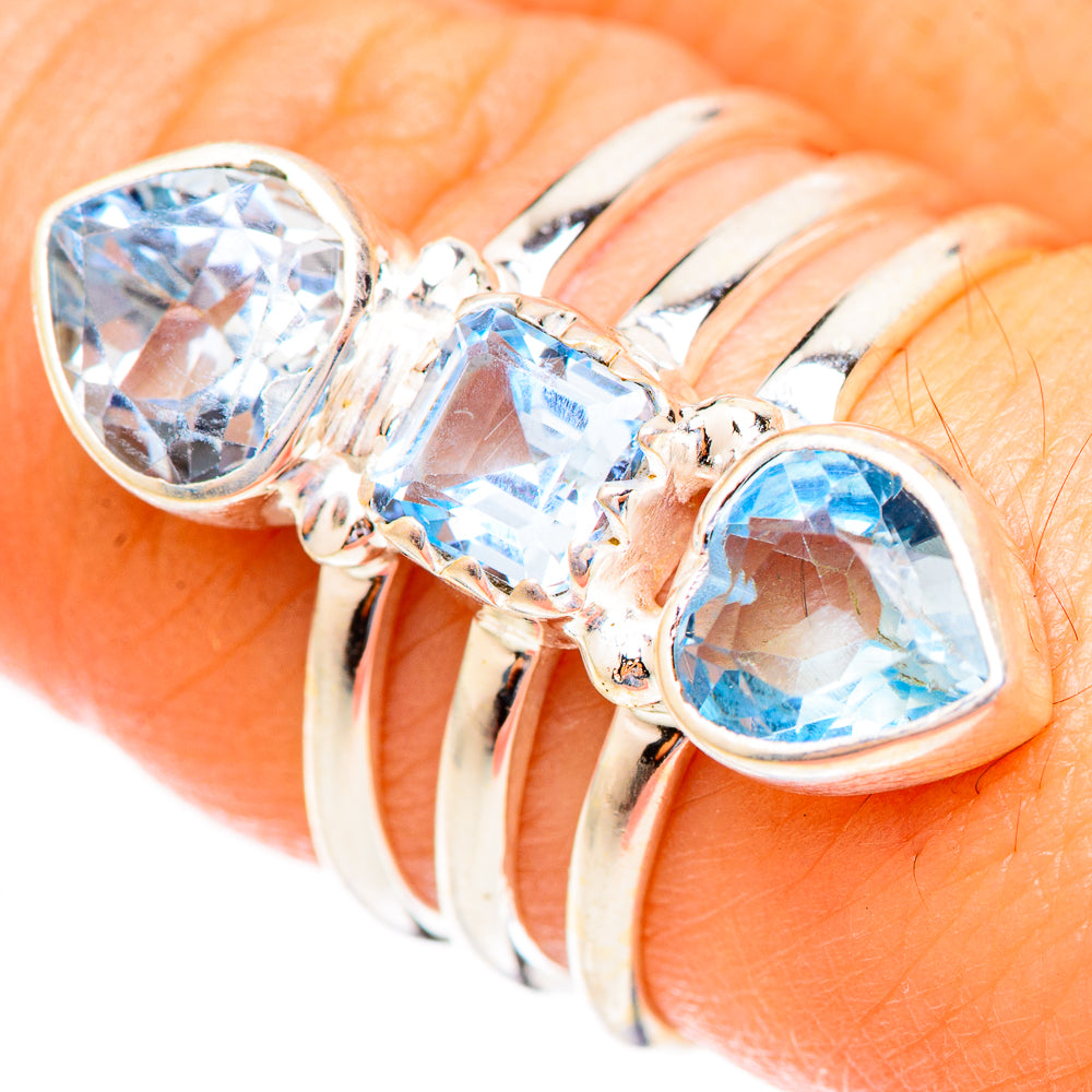 Three-stone ring with blue oval topaz and polished silver band, close-up detail