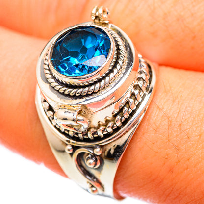 Silver-tone ring with large oval blue gemstone and engraved swirl detailing on the band