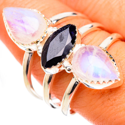 Three-stone silver ring with iridescent white oval stones and dark faceted center