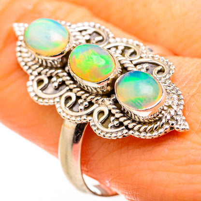 Filigree opal ring on hand: three oval opal cabochons in ornate silver setting, size 10.