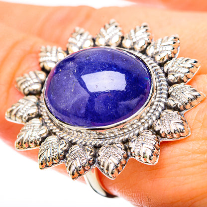 Blue oval gemstone ring on finger, ornate silver leaf setting