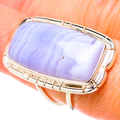 Rectangular blue lace agate ring on finger with silver bezel and side cutouts