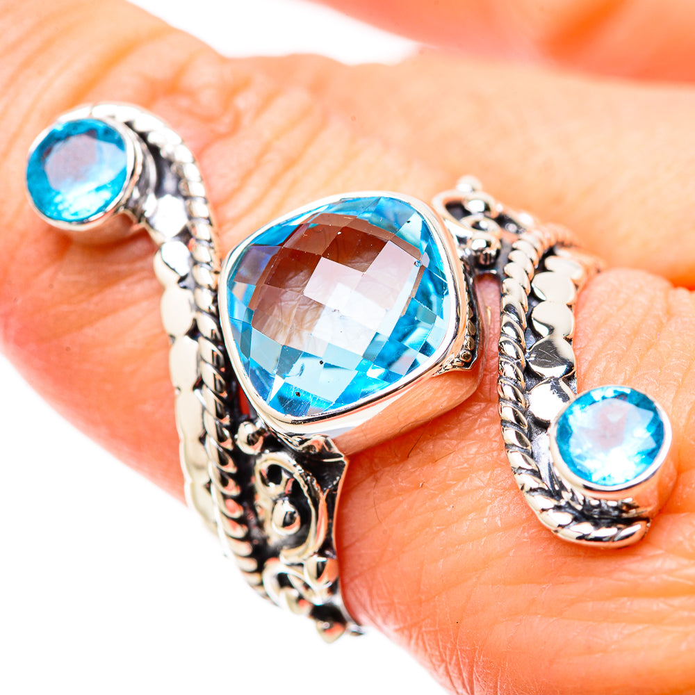 Ornate metal ring with large blue center stone and two small blue stones