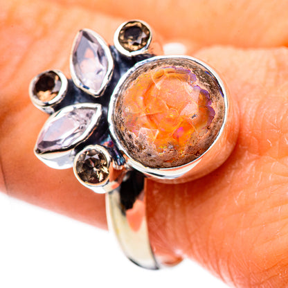 Sterling silver ring with orange opal-like center, surrounded by clear and dark stones