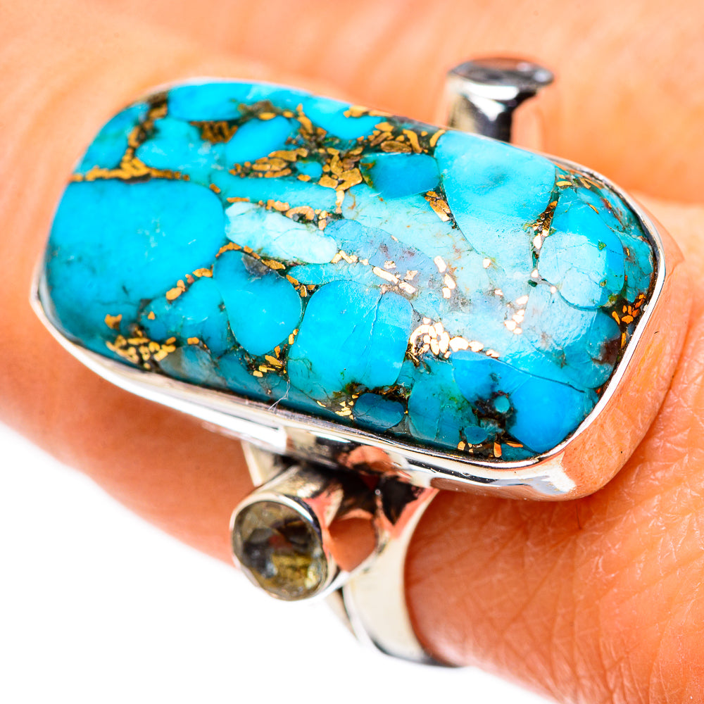 Turquoise cabochon ring with silver frame and gold-brown matrix, close-up view.