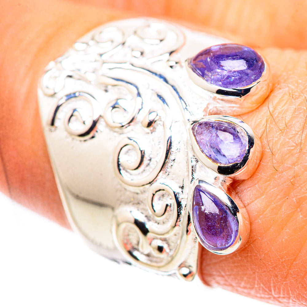 Sterling silver ring close-up with four purple faceted stones in swirling metalwork