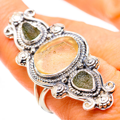 Sterling silver ring on finger with amber center stone and rough green accents