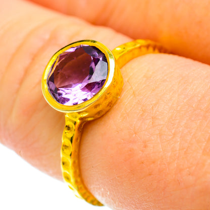Faceted amethyst ring with gold-toned halo and purple gemstone, close-up on top