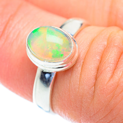Sterling silver opal ring close-up on finger, oval cabochon with green and orange flashes