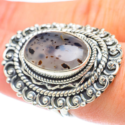 Sterling silver oval agate ring on finger, ornate bezel with speckled cabochon
