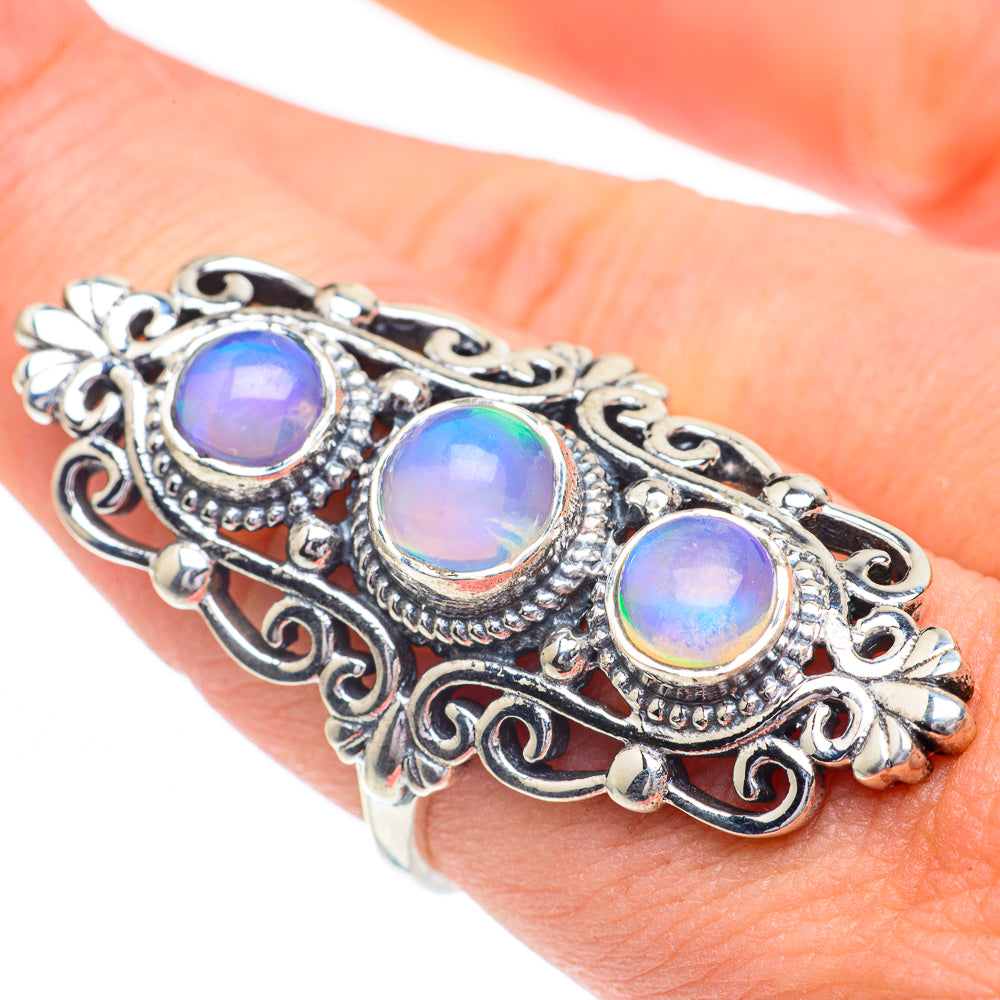 Sterling silver filigree ring with three round opal-like gems in blue and yellow hues.