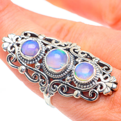 Sterling silver filigree ring with three round opal-like gems in blue and yellow hues.