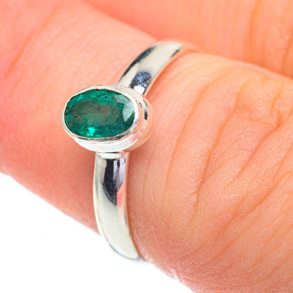 Sterling silver ring detail with oval emerald-green stone on finger