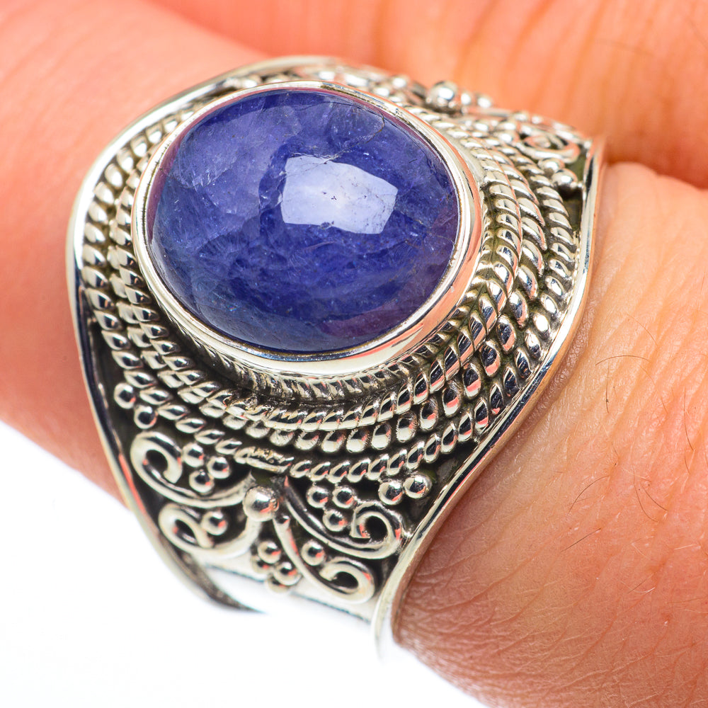 Sterling silver ring on finger with oval blue gemstone centerpiece