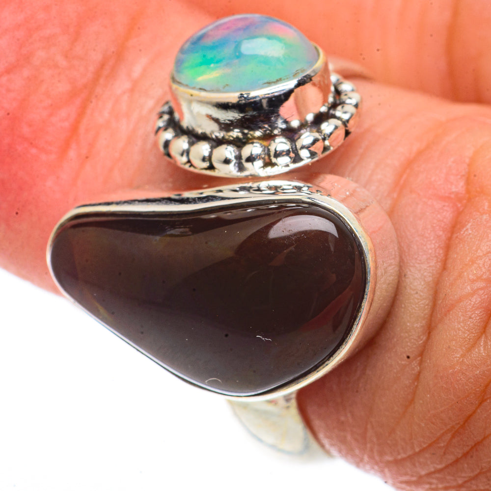 Sterling silver adjustable ring with dark teardrop cabochon and small opal-like stone band.
