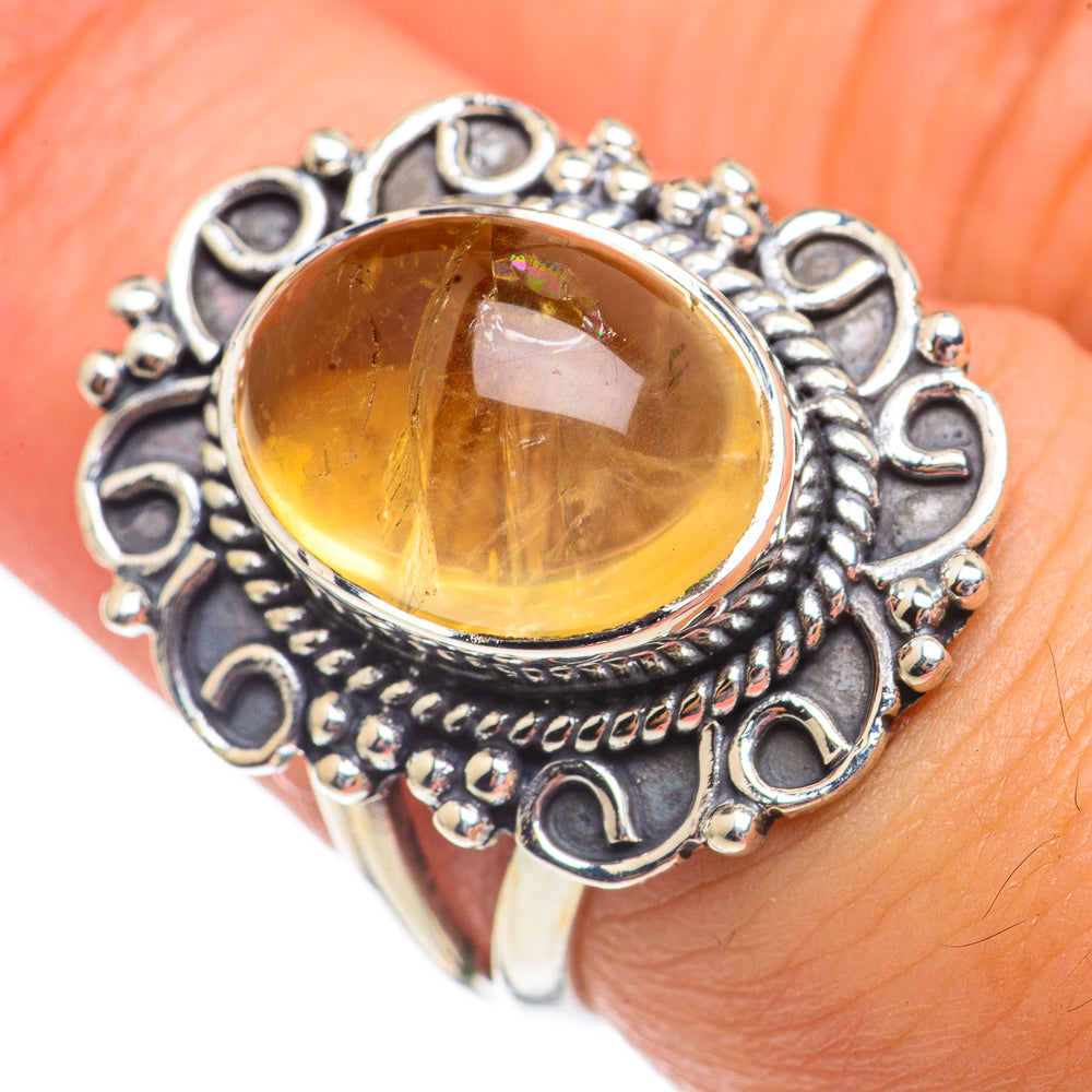 Oval citrine in dark silver filigree ring with openwork bezel on finger