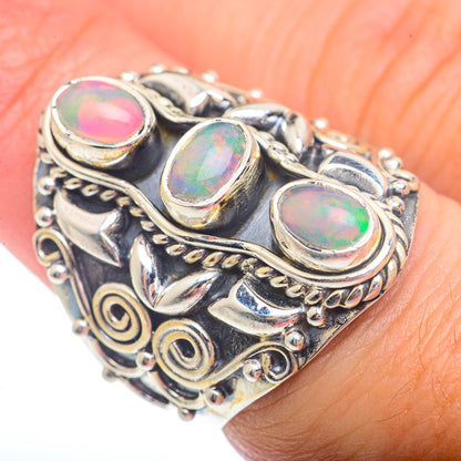 Sterling silver opal ring with three oval opal cabochons, ornate scrollwork on finger