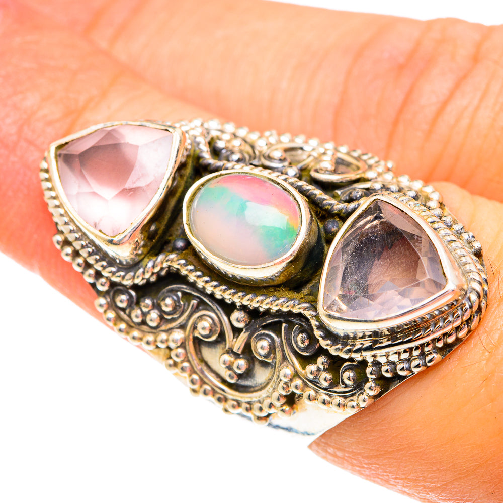 Ornate gemstone ring with oval opal center and two faceted light-pink stones