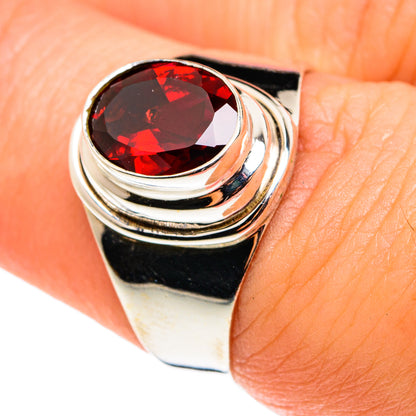 Silver ring with oval red garnet gemstone and layered swirl bezel detail