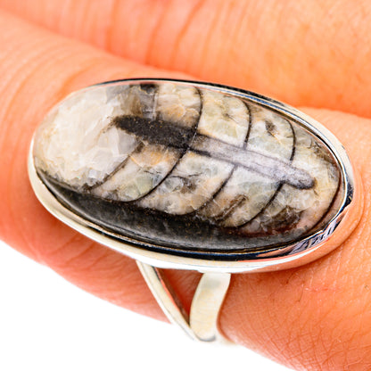 Sterling silver oval orthoceras fossil ring on hand, detailed light-and-dark pattern
