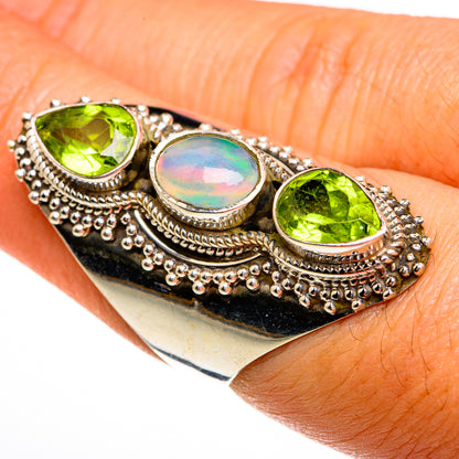 Silver bezel-set ring with three stones: green peridot and iridescent opal on hand