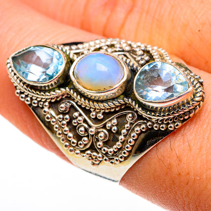 Ornate metal ring with three light-blue oval stones and one round opal center, detailed prongs