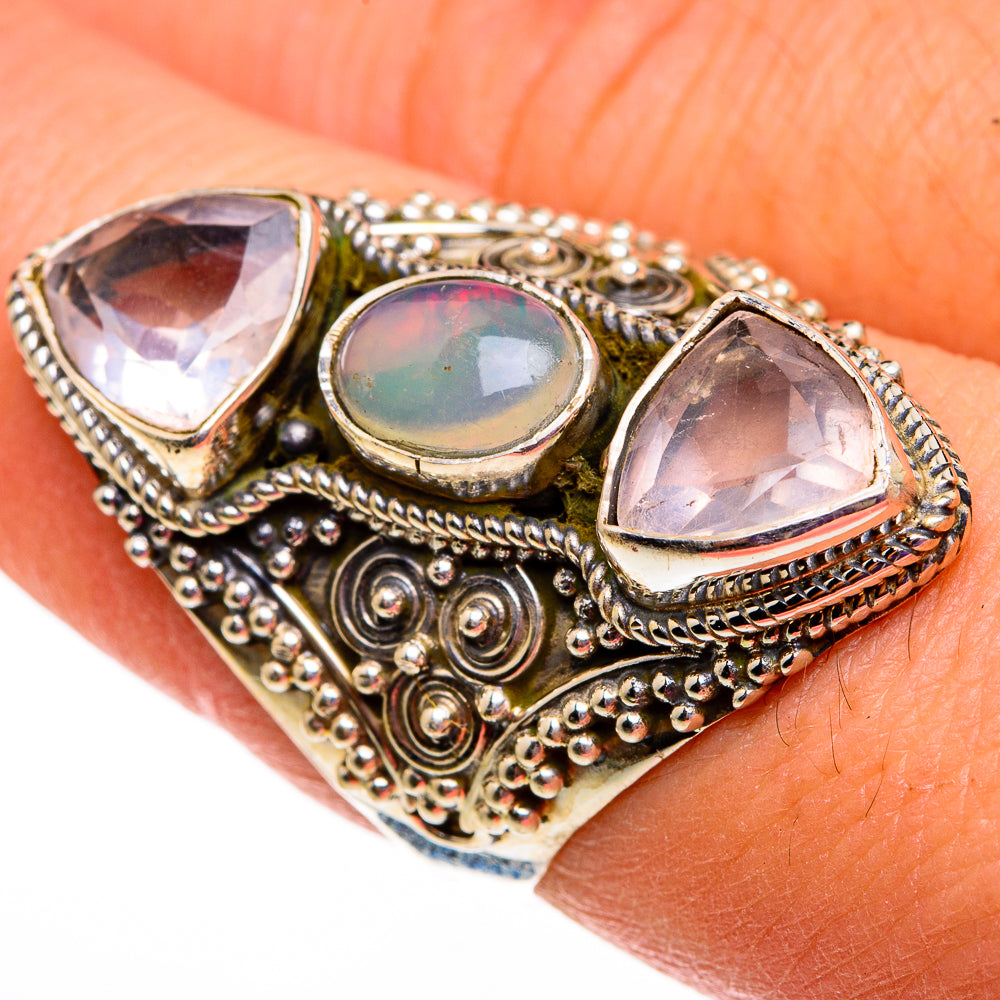 Ornate gold-tone ring on finger with oval opal center and two faceted stones