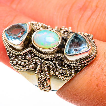 Sterling silver ornate ring with iridescent oval opal and two blue faceted stones