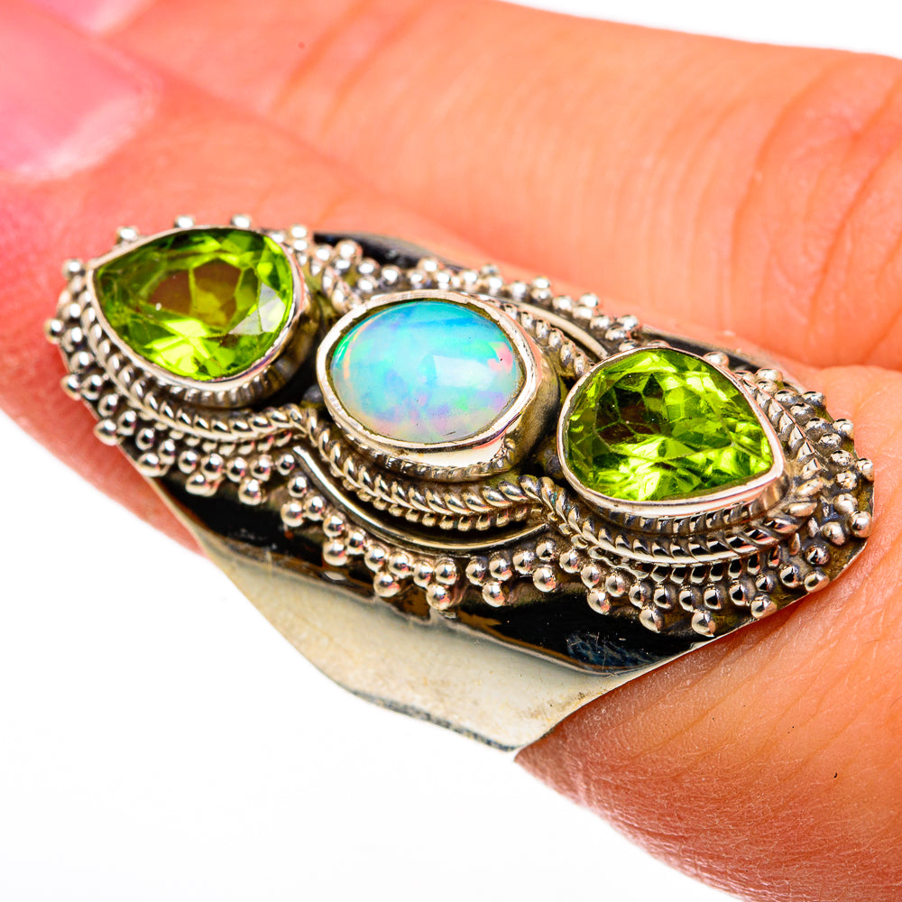 Sterling silver ring with oval opal and two green peridot stones, ornate beaded bezel