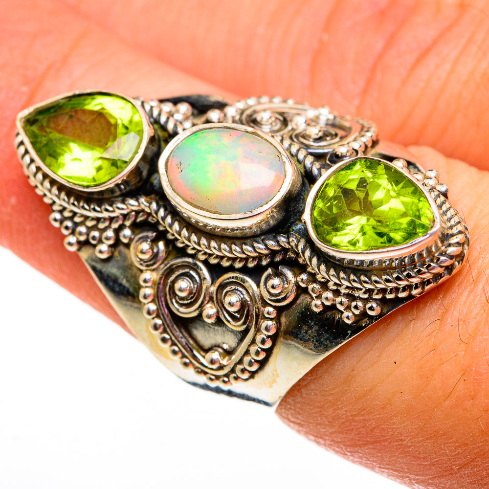 Ornate silver ring with oval opal center, two green peridot stones, filigree setting