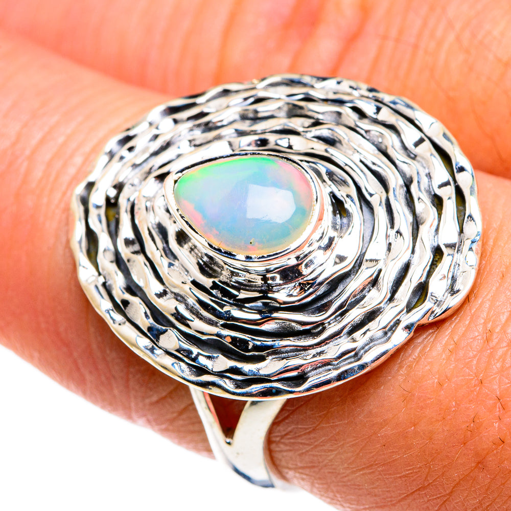 Sterling silver opal ring on finger; oval opal with colorful iridescence