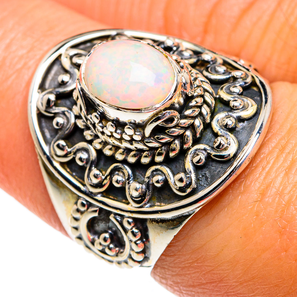 Oval opal cabochon set in vintage-style silver ring with scrolling details