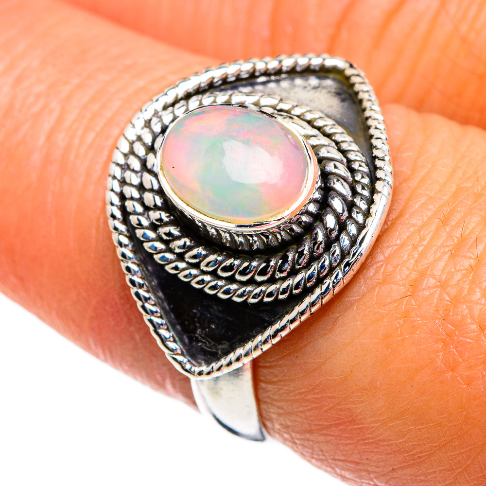 Sterling silver opal ring on finger, oval iridescent opal set in textured bezel; size 7.25