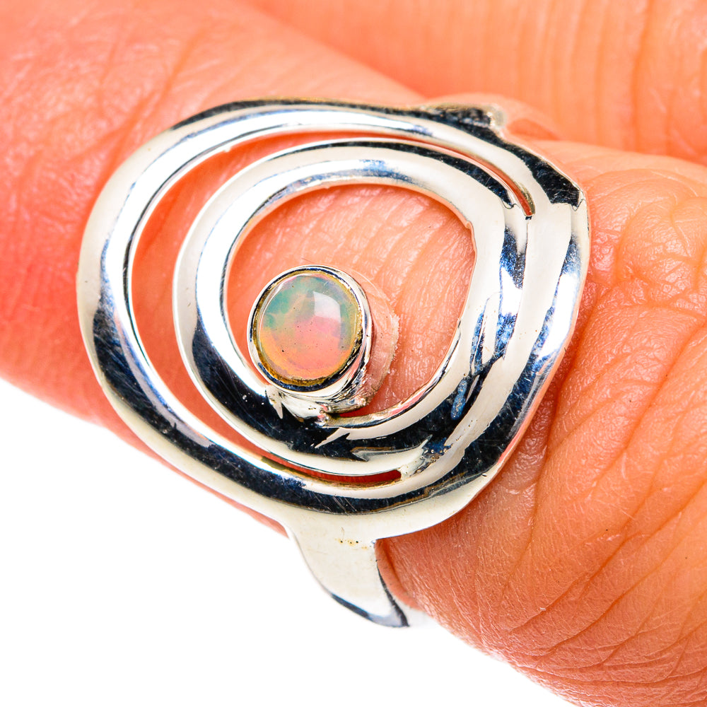 Silver opal ring showing round multicolor stone in curved swirl bezel