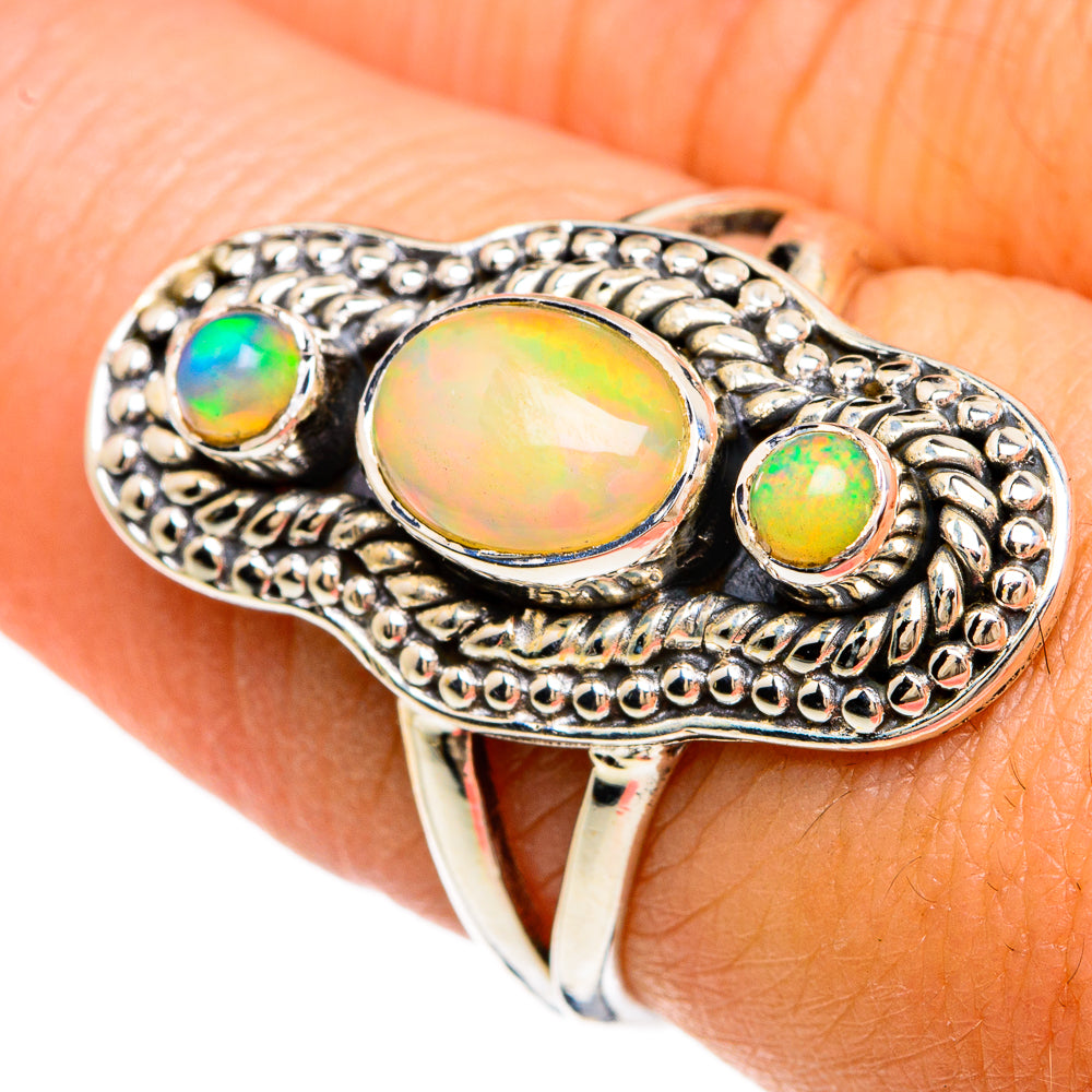 Sterling silver opal ring on finger, oval center with two round green opals, scalloped edge